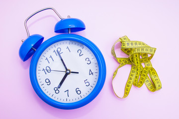 metric tape and alarm clock, concept of diet and slimming