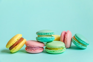 Fototapeta na wymiar Sweet almond colorful pink blue yellow green macaron or macaroon dessert cake isolated on trendy blue pastel background. French sweet cookie. Minimal food bakery concept. Flat lay top view copy space