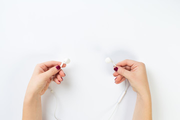 two female hands holding white headphones on an isolated white background