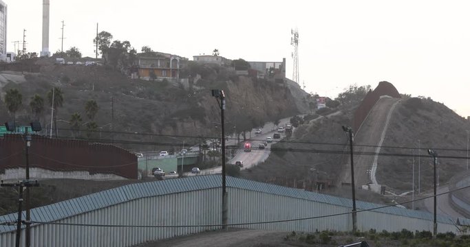 Tijuana Mexico city traffic across security wall. Immigration control of illegal border crossing. United States of America and Mexico. Urban cities on both sides with heavy traffic. 