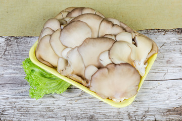 Uncooked oyster mushrooms  on foam food tray on wooden surface