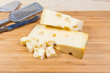 Partly sliced Swiss-type cheese on wooden cutting board