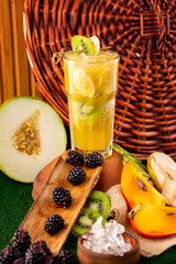 Verical glass of tropical healthy banana fruit cocktail at decorated with fruits and berries table background.