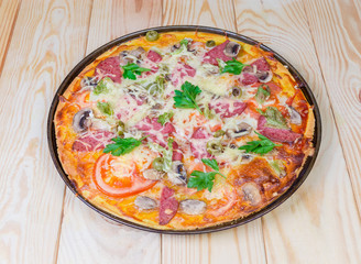 Cooked round pizza with salami on the rustic wooden table