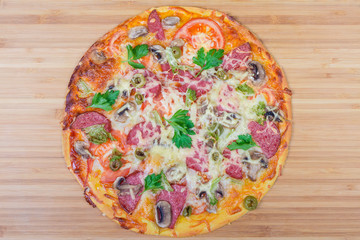 Cooked pizza with salami close-up on wooden cutting board