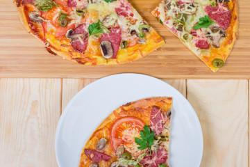 Sliced pizza with salami on dish and cutting board