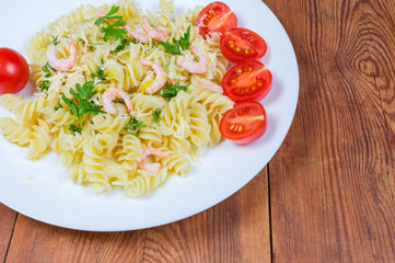 Cooked spiral pasta with shrimps, cheese, cherry tomatoes close-up