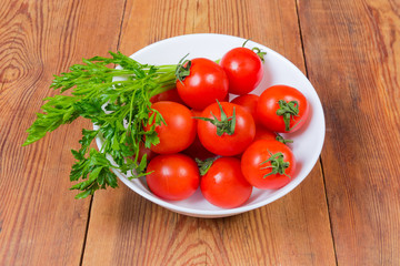 Red cherry tomatoes and parsley in bowl on rustic table