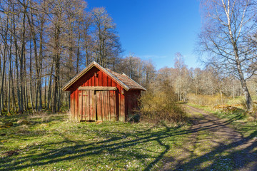 Red wooden shed by a forest road