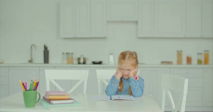 Upset disappointed schoolgirl has difficulties with complicated homework for primary school at home. Caring loving mother consoling and encouraging her little daughter to do difficult schoolwork .