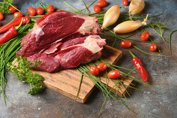 Fresh dark meat with ingredients for cooking on brown wooden cutting board. Hunting composition. Wildanimal hunting.