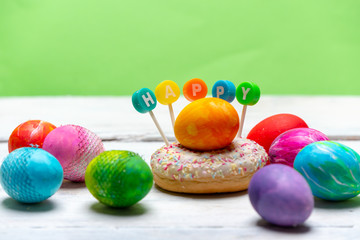 very colorful, brightly painted eggs next to a colorful donut with the word HAPPY