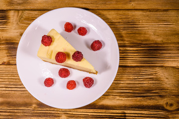 White plate with cheesecake New York and raspberries on wooden table. Top view