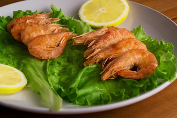 Fried shrimp on a plate with lettuce and lemon. Shrimp grill. Grilled seafood