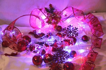 Colorful Christmas and new year background is decorated with lights of garlands, sparkling red balls, snowflake and decorative ribbon on the background. abstract heart of red ribbon