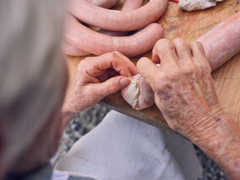 Elderly person sewing natural sausage