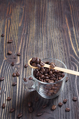Coffee beans in a glass cup with a wooden spoon