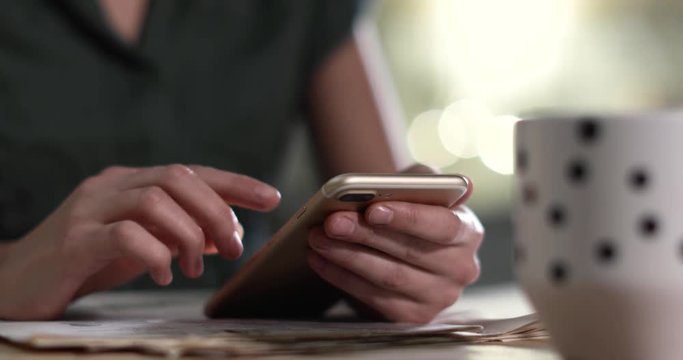Woman using mobile phone at table indoors, closeup

