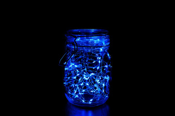 Blue fairy light in a glass jar, in the dark, low-key photography