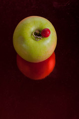 manzana verde, fondo rojo, tomate reflejo