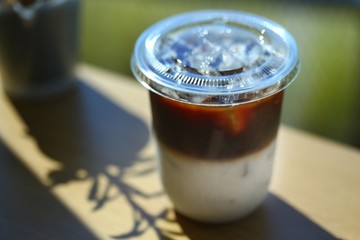 Plastic glass of Iced coffee in coffee shop. Selective focus and free space for text. Industrial food and drink concept.