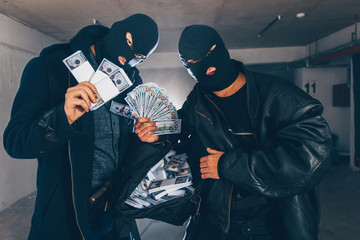 Bandits holding money in the garage