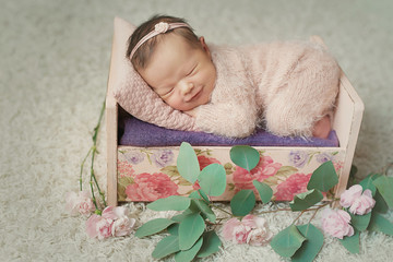 Cute newborn little girl sleeping in crib with flowers. Baby goods packaging template. Closeup...