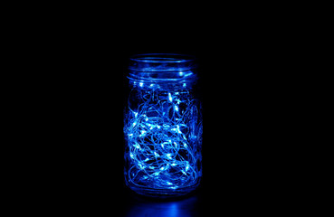 Blue fairy light in a mason jar, in the dark, low-key photography