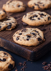 Homemade chocolate cookies on dark old wooden board. Chocolate chips cookies shot.