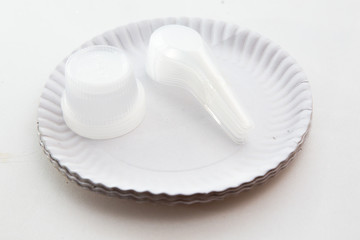 Disposable white paper plate and plastic spoon on white