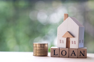 Miniature wooden home put on wooden block word with loan.