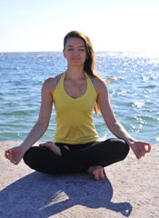 Fototapeta na wymiar Beautiful girl doing yoga by the sea. Healthy lifestyle
