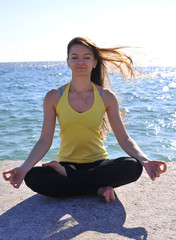Fototapeta na wymiar Beautiful girl doing yoga by the sea. Healthy lifestyle