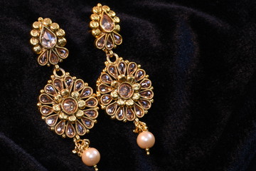 Pair of Golden earrings close up macro image on black background