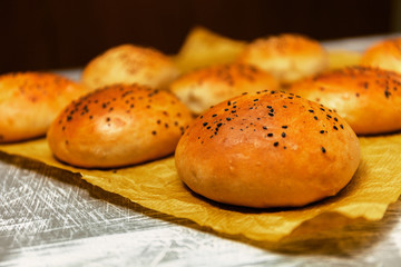 Freshly baked burger buns with black sesame on a baking paper. Fresh from the oven.