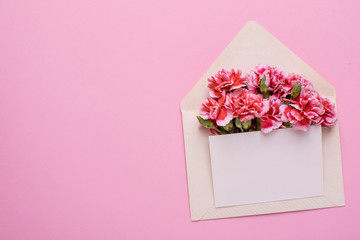 An envelope with pink flowers and a present card on a pink background