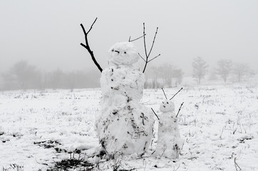 creepy snowmen from dirty snow on the background of trees and fog