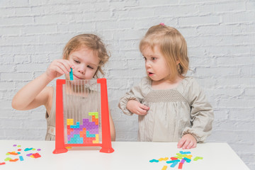 Fototapeta premium child, girl in a dress playing logic designer, on a white wall background