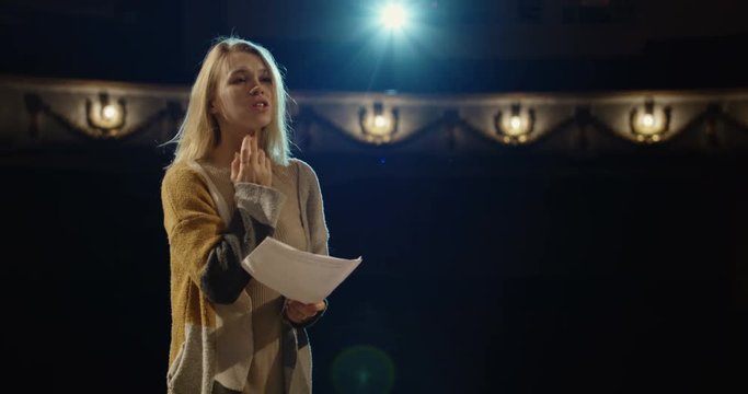Medium shot of an actor and an actress rehearsing a romantic scene in a theater while holding their scripts
