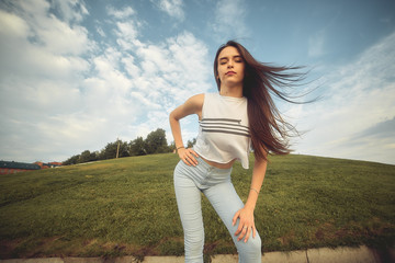 a young girl dancing on the street in the summer in the city against the green grass.