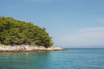 Naklejka premium Beautiful coastline with green forest, stones and blue sky and sea water. Natural wallpaper. Adriatic coastline. Croatia. Mediterranean sea.