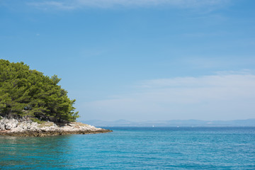 Beautiful coastline with green forest, stones and blue sky and sea water. Natural wallpaper. Adriatic coastline. Croatia. Mediterranean sea.