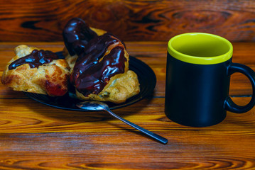 Coffee and chocolate eclairs on a wooden background