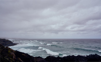 Tenerife: Black Stone Coast overlooking the rough Atlantic Sea on a rainy day, waves braking