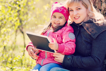 Family, technology and people concept - happy smiling young daughter with tablet pc computer and...