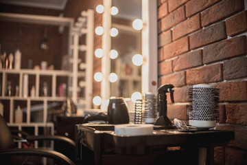 Round hairbrush and other tools in the beauty salon. Focus on the comb. Shallow depth of field