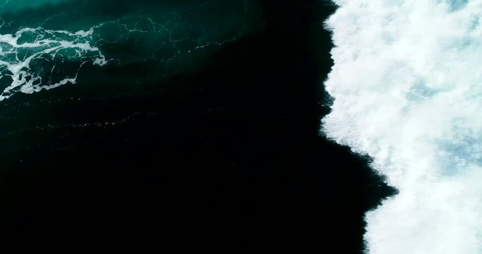 Slow motion top down aerial view of giant ocean waves crashing on sunny day 