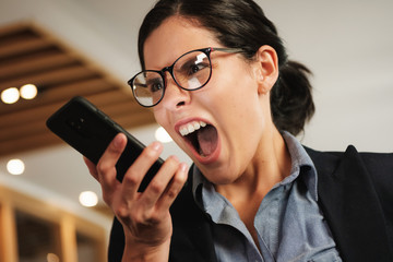 Hysterical Angry Business Woman Screaming Madly at her Smartphone - obrazy, fototapety, plakaty