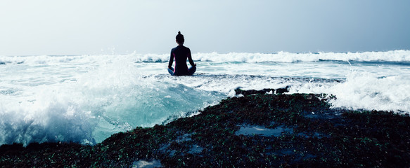 Woman practice yoga at the seaside coral cliff edge