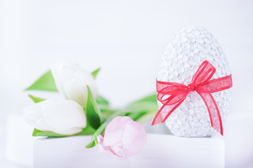 Happy Easter! Easter egg and delicate tulips on a white background. Copy space